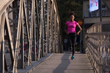 Image showing african american woman running across the bridge