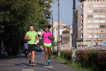 Image showing young smiling multiethnic couple jogging in the city