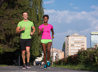 Image showing young smiling multiethnic couple jogging in the city