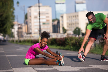 Image showing jogging couple warming up and stretching in the city