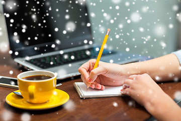 Image showing close up of woman writing to notebook with pencil