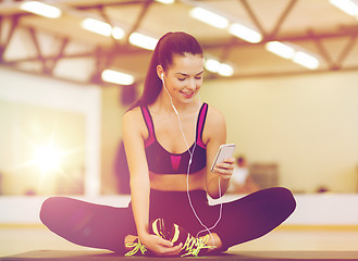 Image showing smiling woman stretching on mat in the gym