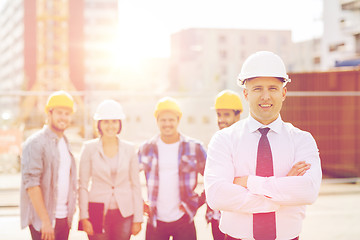 Image showing group of smiling builders in hardhats outdoors