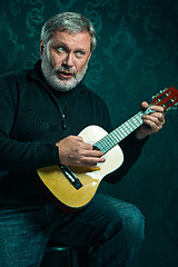 Image showing Studio portrait of senior man with guitar.