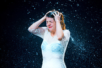 Image showing The young girl standing under running water