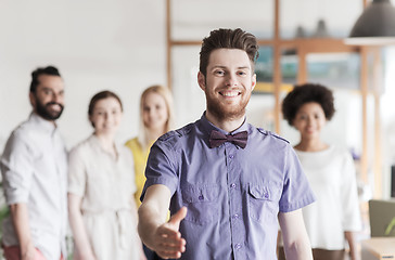 Image showing happy man making handshake over office team