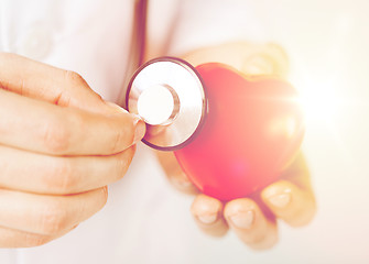 Image showing male hands holding red heart and stethoscope