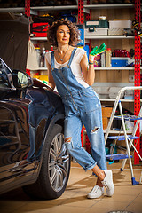 Image showing smiling woman car mechanic with the instructions in blue overall
