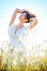 Image showing pretty happy woman in bright clothing among spikes in field