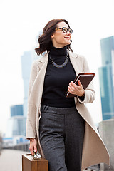 Image showing Smiling beautiful middle-aged woman goes in a white coat 