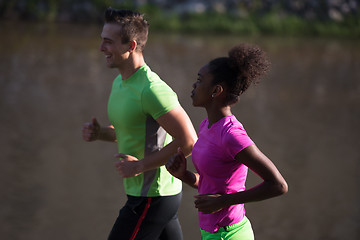 Image showing young smiling multiethnic couple jogging in the city