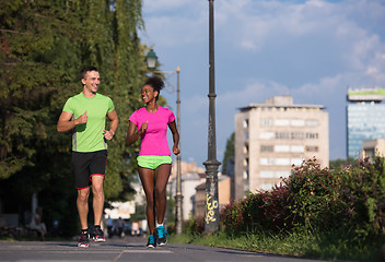 Image showing young smiling multiethnic couple jogging in the city