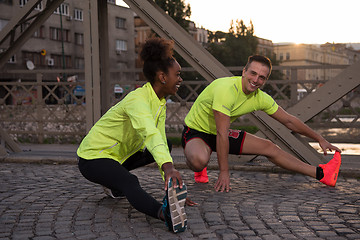 Image showing jogging couple warming up and stretching in the city