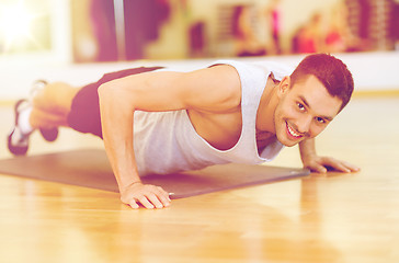 Image showing smiling man doing push-ups in the gym