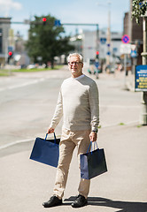 Image showing senior man with shopping bags walking in city