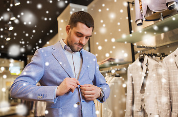 Image showing happy young man trying jacket on in clothing store