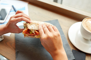 Image showing woman eating salmon panini sandwich at restaurant