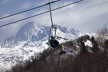 Image showing Skiers on ski-lift in snow mountains at winter sun day