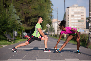 Image showing jogging couple warming up and stretching in the city