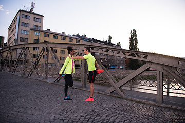 Image showing jogging couple warming up and stretching in the city