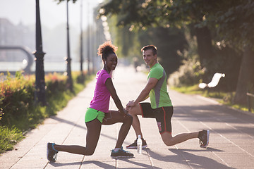 Image showing jogging couple warming up and stretching in the city