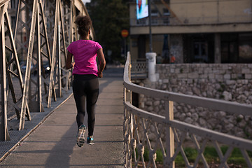 Image showing african american woman running across the bridge