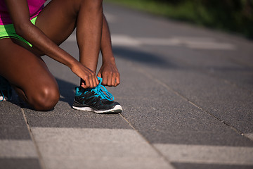 Image showing African american woman runner tightening shoe lace