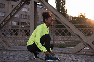 Image showing African american woman runner tightening shoe lace