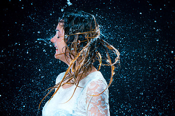 Image showing The young girl standing under running water