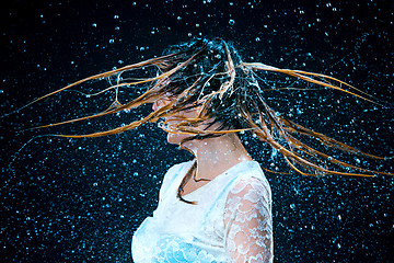 Image showing The young girl standing under running water