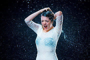 Image showing The young girl standing under running water