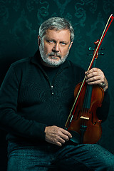 Image showing Senior musician playing a violin with wand on black background