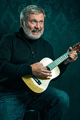 Image showing Studio portrait of senior man with guitar.