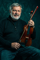 Image showing Senior musician playing a violin with wand on black background