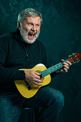 Image showing Studio portrait of senior man with guitar.