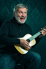 Image showing Studio portrait of senior man with guitar.