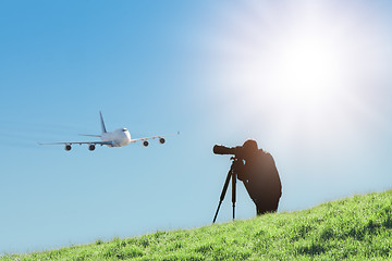 Image showing Silhouette of spotter photographer capturing photos of landing airplane