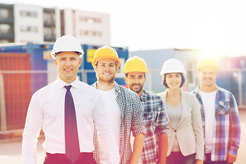 Image showing group of smiling builders in hardhats outdoors