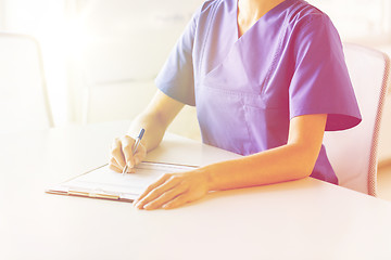 Image showing close up of doctor or nurse writing to clipboard