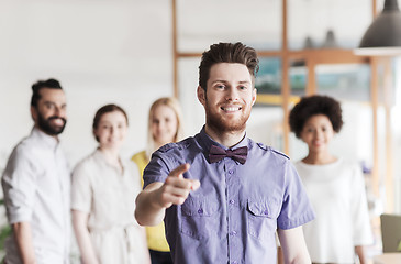 Image showing happy man pointing finger at you over office team
