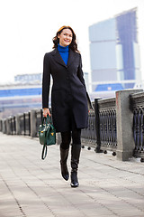 Image showing beautiful smiling woman in dark coat with handbag and laptop