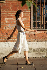 Image showing beautiful woman in a white dress goes on old street