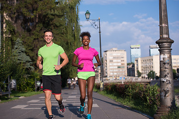 Image showing young smiling multiethnic couple jogging in the city