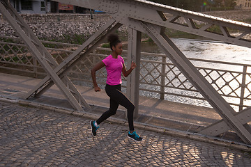 Image showing african american woman running across the bridge