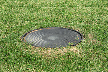 Image showing Metal manhole in a background of green grass on the field