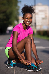 Image showing African american woman runner tightening shoe lace