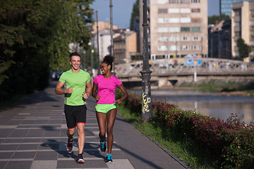 Image showing young smiling multiethnic couple jogging in the city