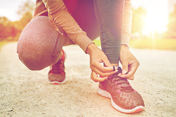 Image showing close up of woman tying shoelaces outdoors