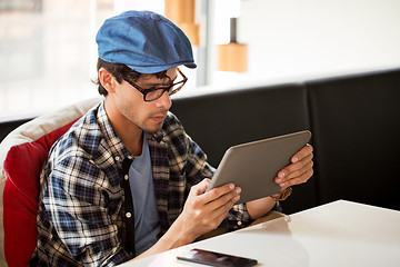 Image showing man with tablet pc sitting at cafe table