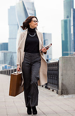 Image showing beautiful smiling middle-aged woman in a bright coat goes with a